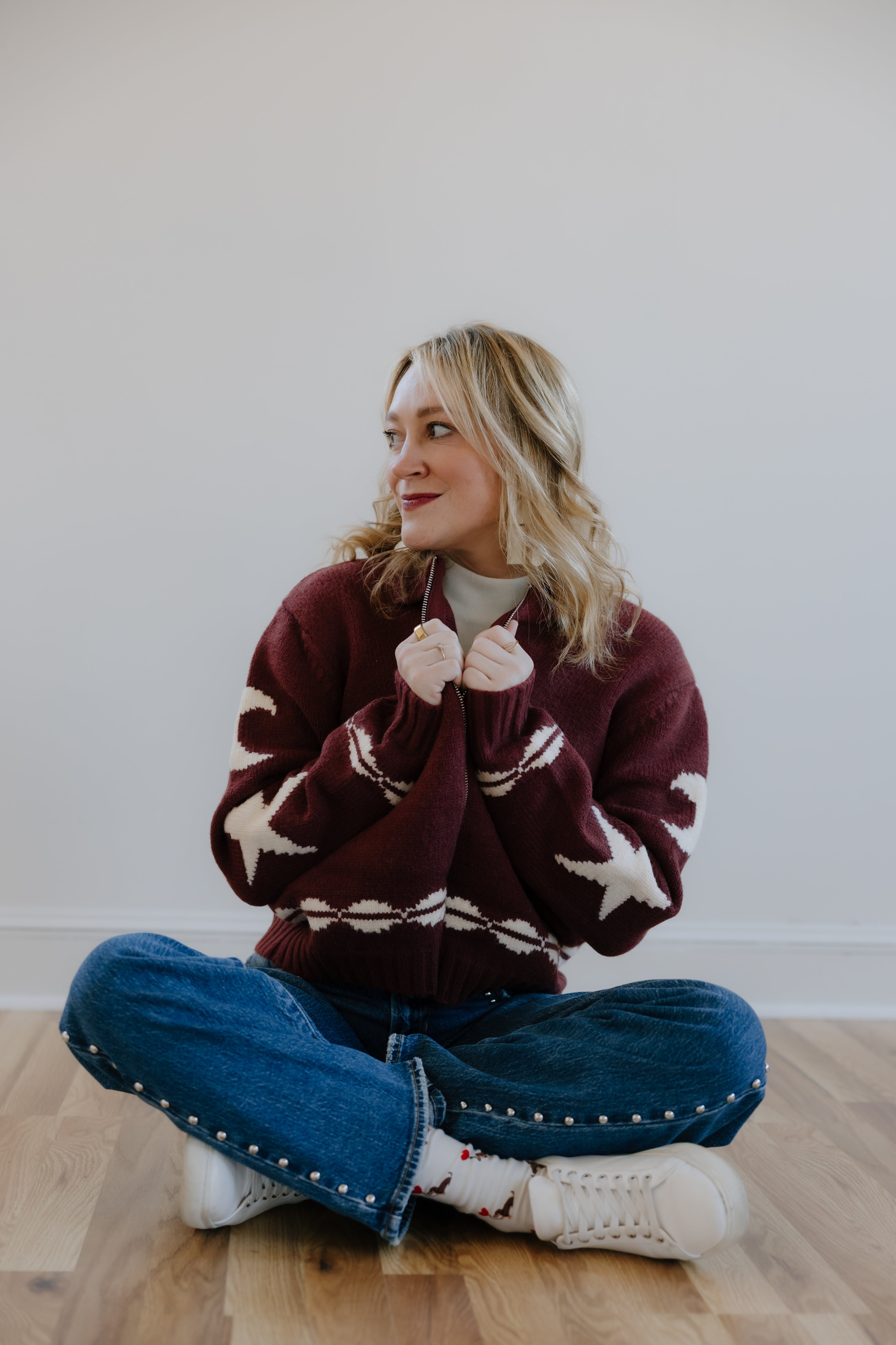 Burgundy full zip collared sweater with western pattern and studded straight leg jeans