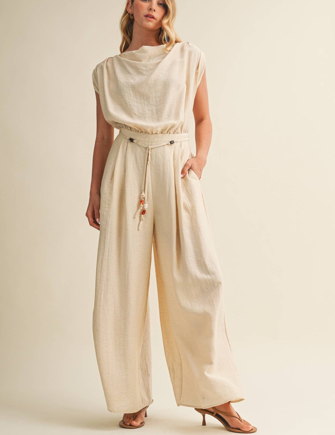 cream wide leg jumpsuit, cowl neck jumpsuit, linen blend jumpsuit, neutral one piece outfit, drawstring waist jumpsuit, resort wear jumpsuit, cap sleeve jumpsuit, flowy wide leg romper, elegant casual jumpsuit, women's cream jumpsuit