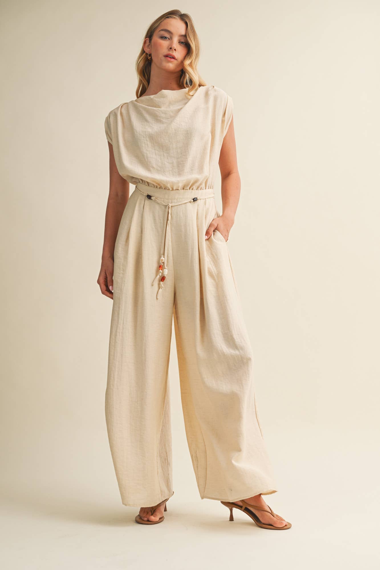 cream wide leg jumpsuit, cowl neck jumpsuit, linen blend jumpsuit, neutral one piece outfit, drawstring waist jumpsuit, resort wear jumpsuit, cap sleeve jumpsuit, flowy wide leg romper, elegant casual jumpsuit, women's cream jumpsuit