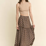 an earthy brown check midi skirt with an elastic waist, flowy tiered silhouette and feminine ruffle trim. available in sizes small through 3xl.