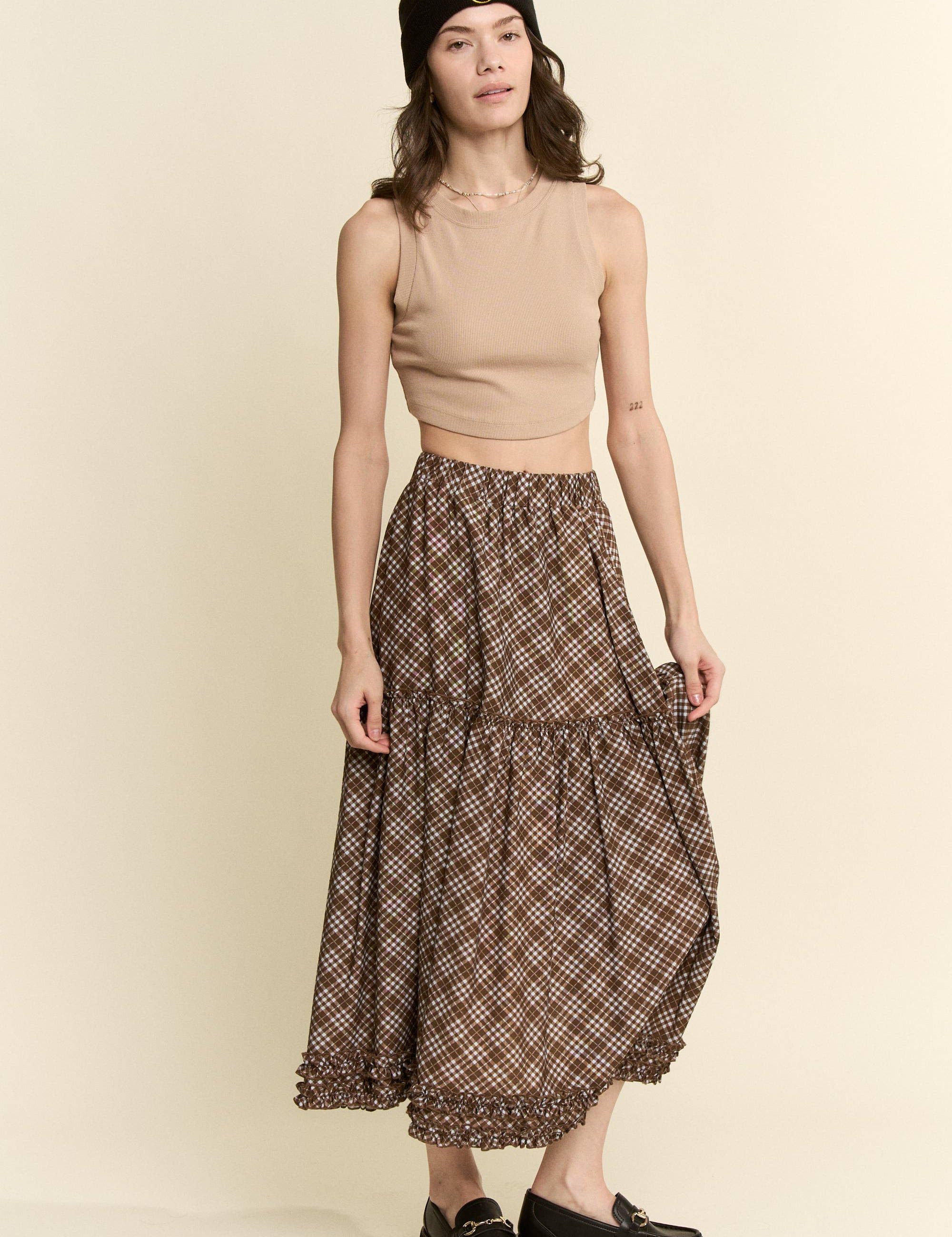 an earthy brown check midi skirt with an elastic waist, flowy tiered silhouette and feminine ruffle trim. available in sizes small through 3xl.