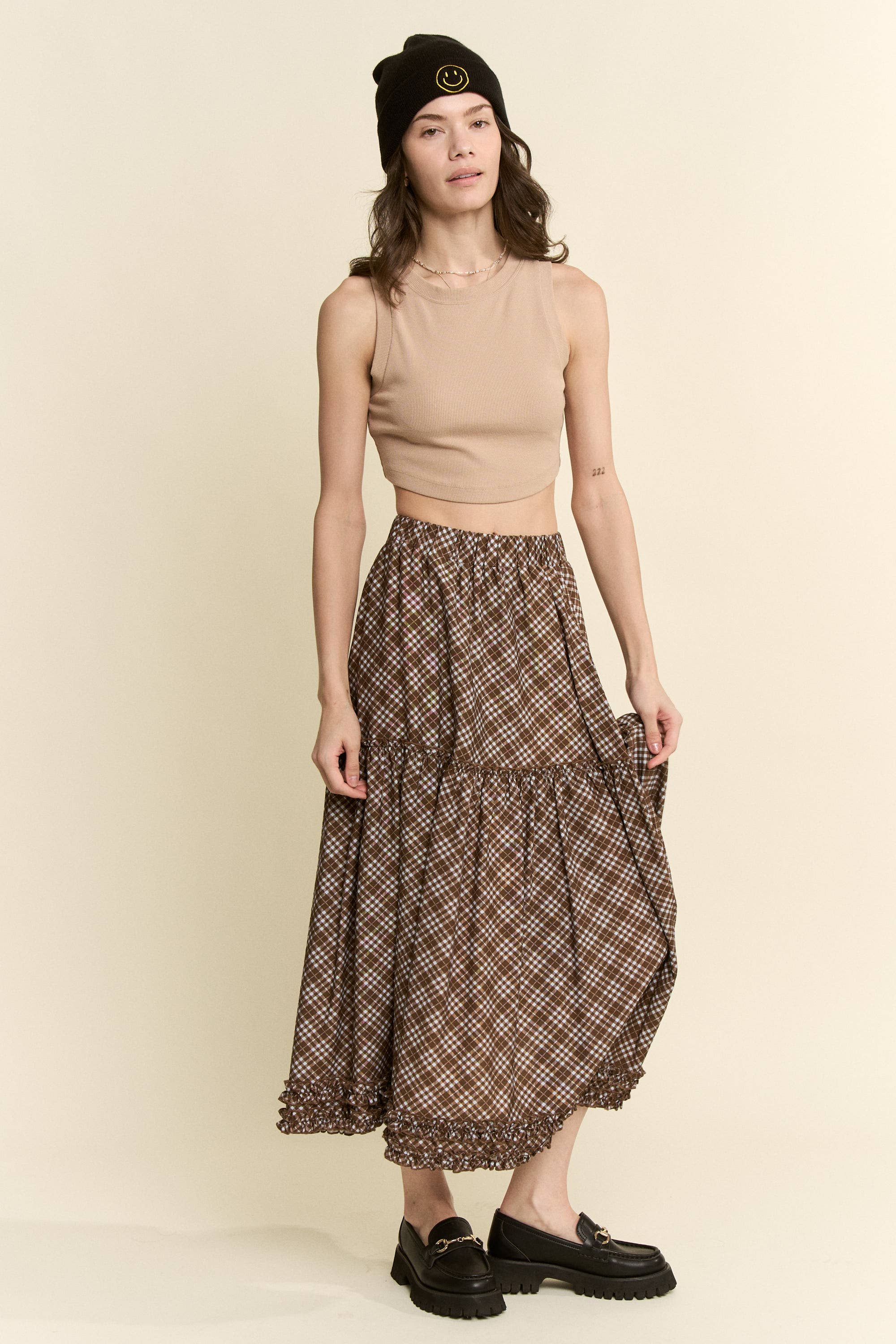 an earthy brown check midi skirt with an elastic waist, flowy tiered silhouette and feminine ruffle trim. available in sizes small through 3xl.
