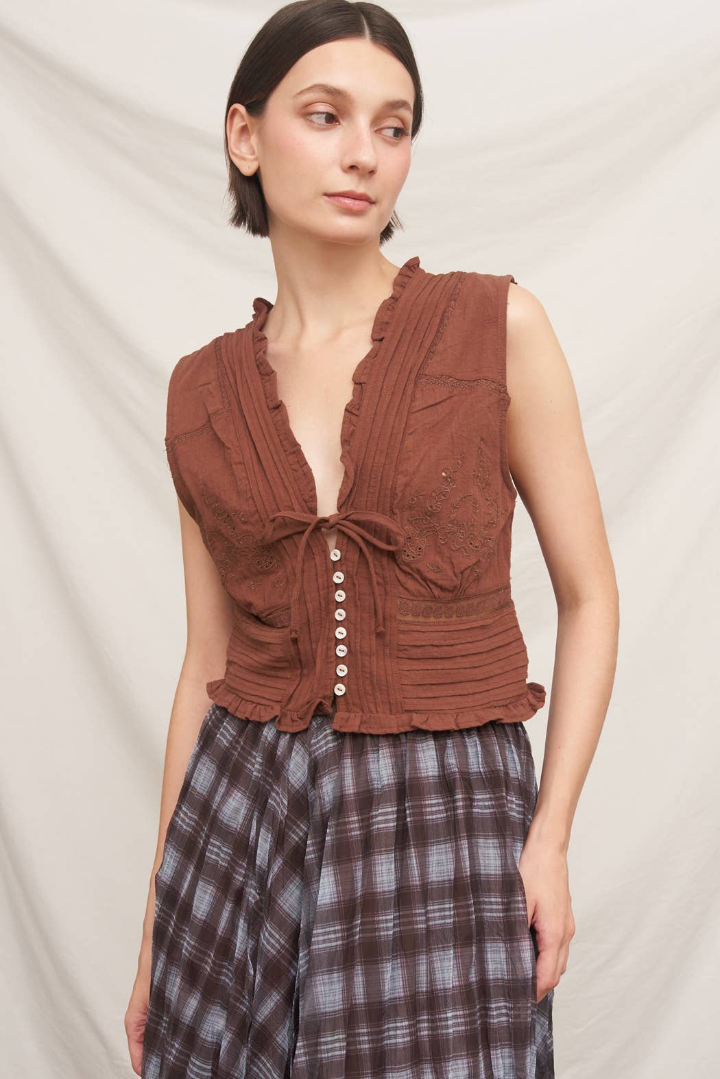 rust brown sleeveless embroidered blouse with v-neck tie, pintuck details, ruffled trim and button front