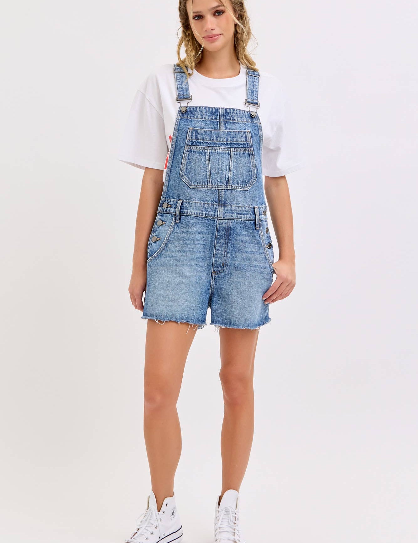 medium wash denim shortalls with square neckline
women's denim overalls shorts with side buttons
relaxed fit cotton denim shortalls
classic blue jean shortalls for women
summer denim overalls styled with white tank top
medium wash denim romper overalls with pockets
casual cotton shortalls for summer
vintage inspired denim shortalls with adjustable straps