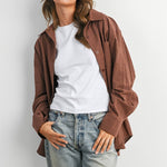 woman wearing an oversized rust brown micro check button-down shirt with long sleeves and buttoned back split detail