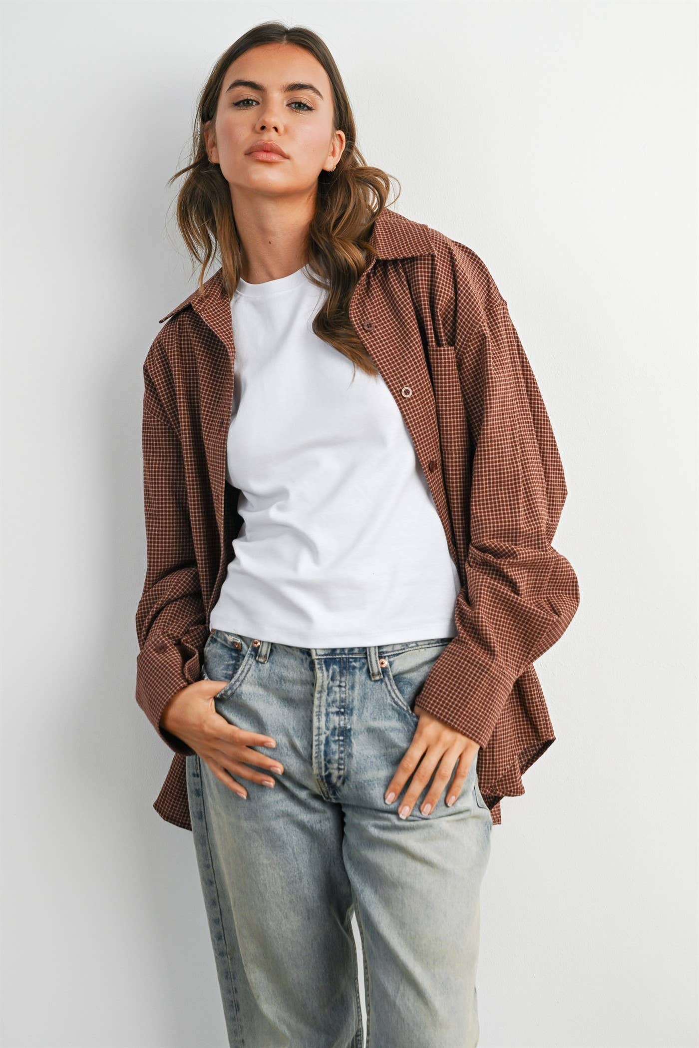 woman wearing an oversized rust brown micro check button-down shirt with long sleeves and buttoned back split detail