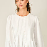 women's white button front blouse with pintuck pleats, long puff sleeves, round neckline, and ruffled babydoll hem