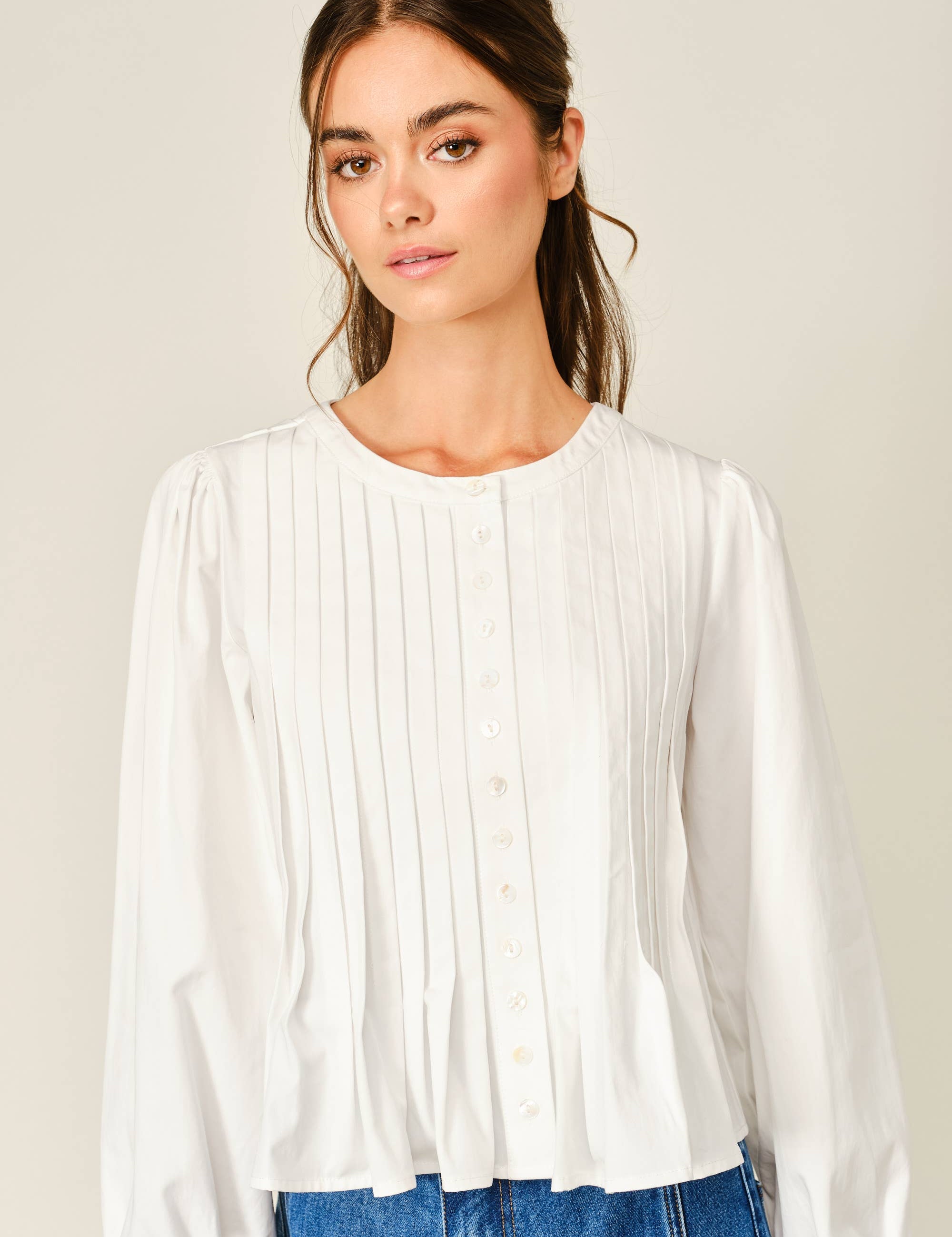 women's white button front blouse with pintuck pleats, long puff sleeves, round neckline, and ruffled babydoll hem