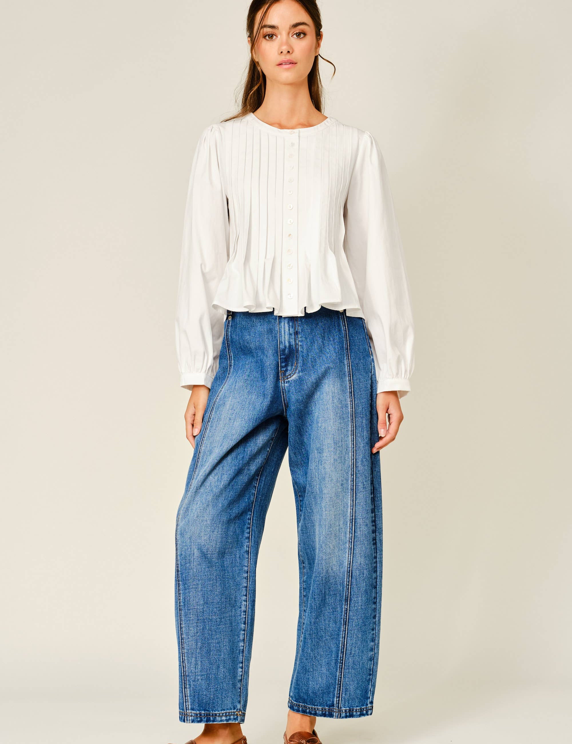women's white button front blouse with pintuck pleats, long puff sleeves, round neckline, and ruffled babydoll hem