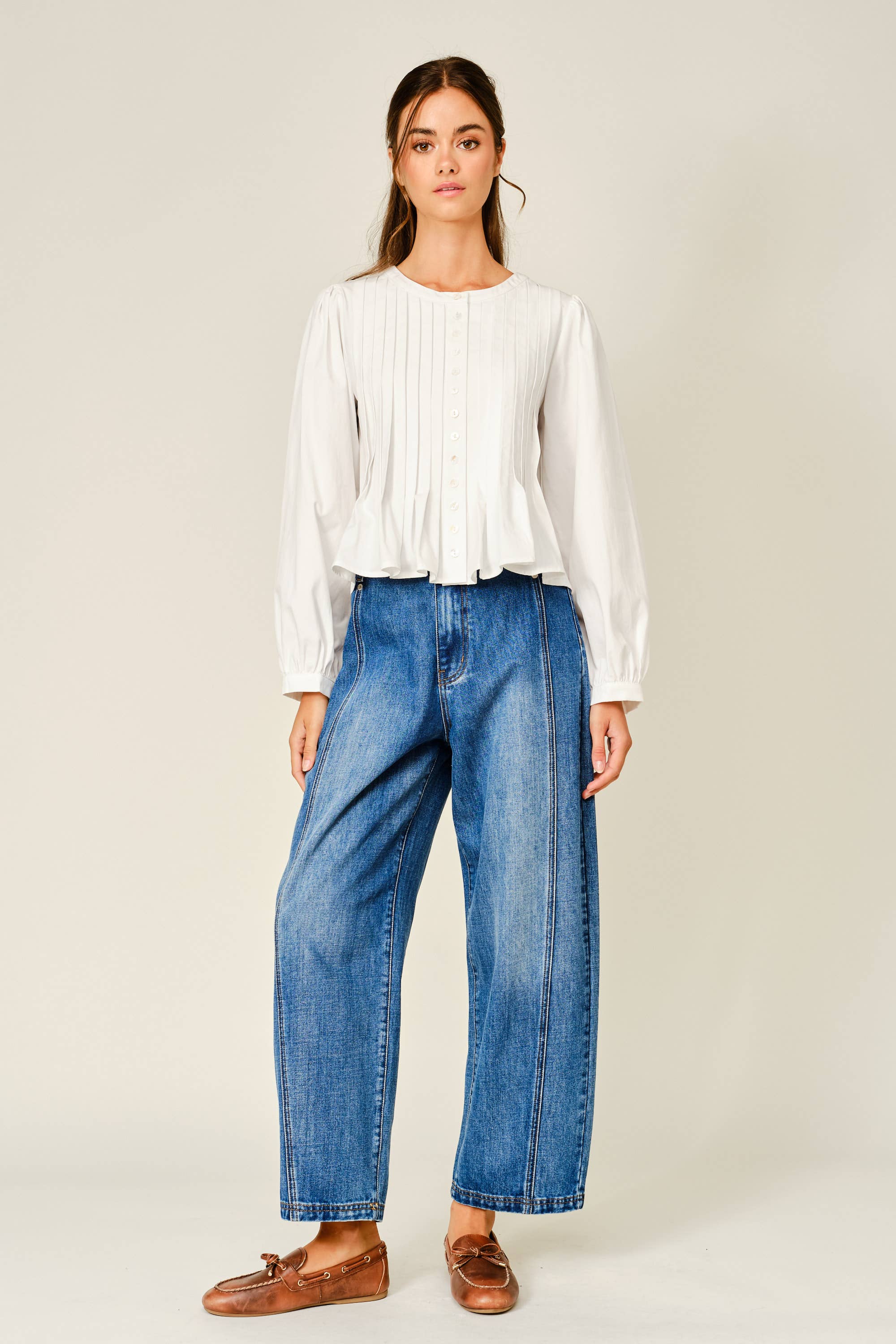 women's white button front blouse with pintuck pleats, long puff sleeves, round neckline, and ruffled babydoll hem