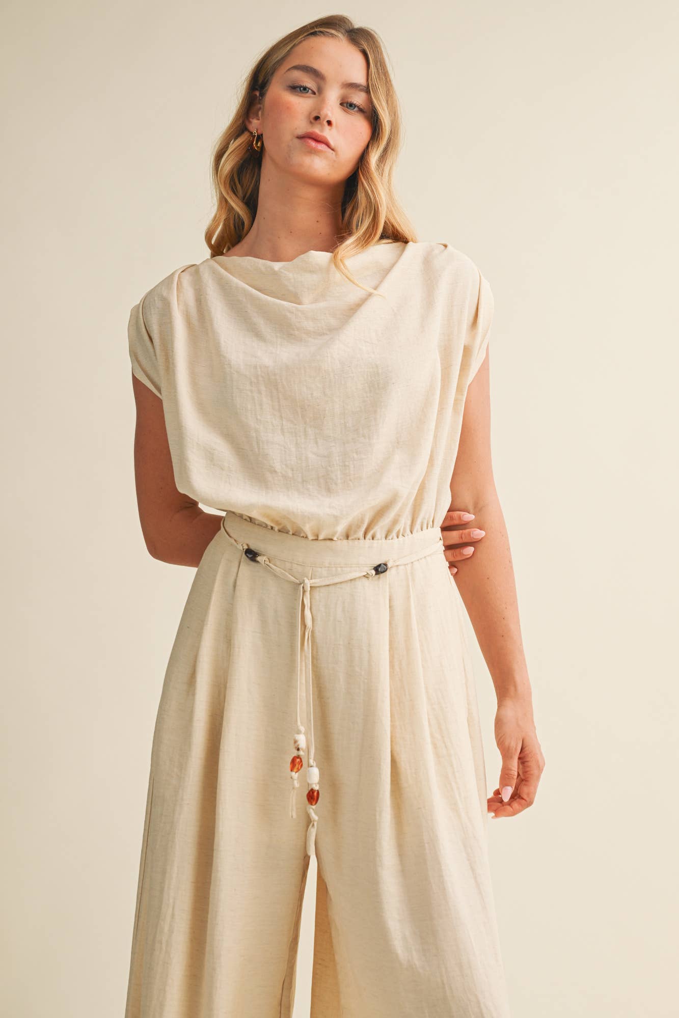 ream wide leg jumpsuit, cowl neck jumpsuit, linen blend jumpsuit, neutral one piece outfit, drawstring waist jumpsuit, resort wear jumpsuit, cap sleeve jumpsuit, flowy wide leg romper, elegant casual jumpsuit, women's cream jumpsuit