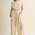 ream wide leg jumpsuit, cowl neck jumpsuit, linen blend jumpsuit, neutral one piece outfit, drawstring waist jumpsuit, resort wear jumpsuit, cap sleeve jumpsuit, flowy wide leg romper, elegant casual jumpsuit, women's cream jumpsuit