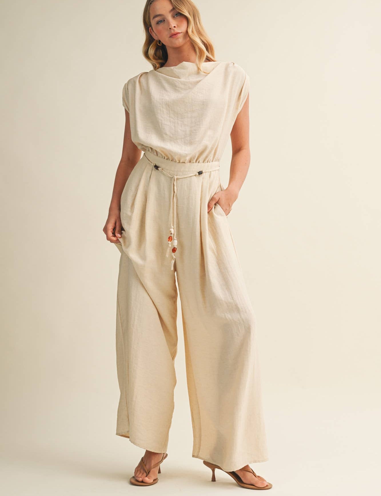 ream wide leg jumpsuit, cowl neck jumpsuit, linen blend jumpsuit, neutral one piece outfit, drawstring waist jumpsuit, resort wear jumpsuit, cap sleeve jumpsuit, flowy wide leg romper, elegant casual jumpsuit, women's cream jumpsuit