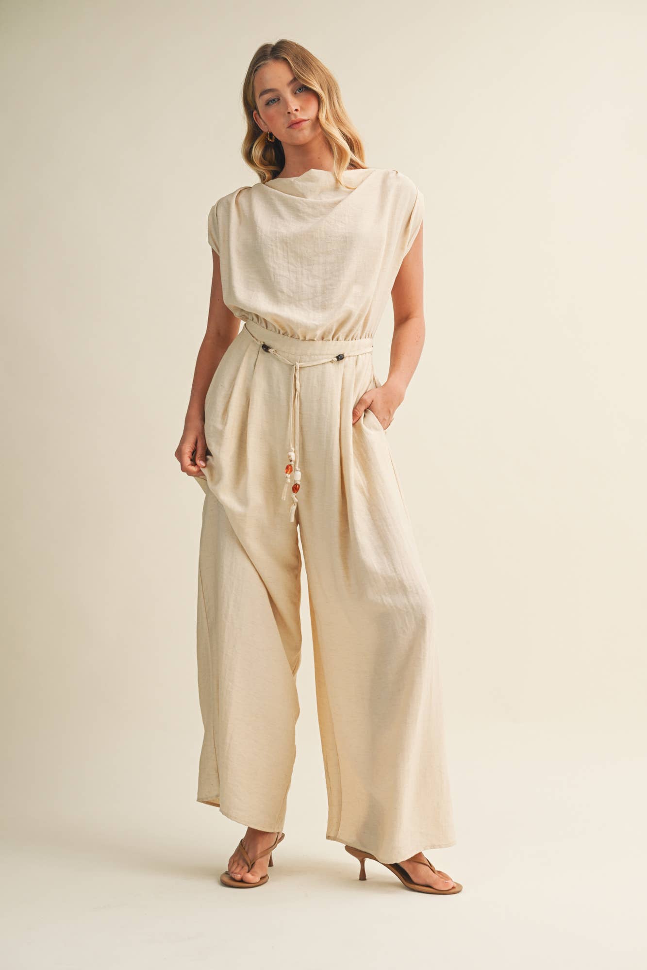 ream wide leg jumpsuit, cowl neck jumpsuit, linen blend jumpsuit, neutral one piece outfit, drawstring waist jumpsuit, resort wear jumpsuit, cap sleeve jumpsuit, flowy wide leg romper, elegant casual jumpsuit, women's cream jumpsuit