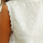 embroidered cotton linen sleeveless top with side ties
white embroidered tank top with relaxed boxy fit
cotton linen sleeveless blouse with tie side detail
lightweight embroidered summer top in white
relaxed fit cotton linen tank with embroidery
white sleeveless top paired with matching linen pants
breathable cotton linen blouse for summer
embroidered neutral top with hip length silhouette