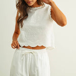 embroidered cotton linen sleeveless top with side ties
white embroidered tank top with relaxed boxy fit
cotton linen sleeveless blouse with tie side detail
lightweight embroidered summer top in white
relaxed fit cotton linen tank with embroidery
white sleeveless top paired with matching linen pants
breathable cotton linen blouse for summer
embroidered neutral top with hip length silhouette