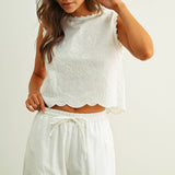 embroidered cotton linen sleeveless top with side ties
white embroidered tank top with relaxed boxy fit
cotton linen sleeveless blouse with tie side detail
lightweight embroidered summer top in white
relaxed fit cotton linen tank with embroidery
white sleeveless top paired with matching linen pants
breathable cotton linen blouse for summer
embroidered neutral top with hip length silhouette