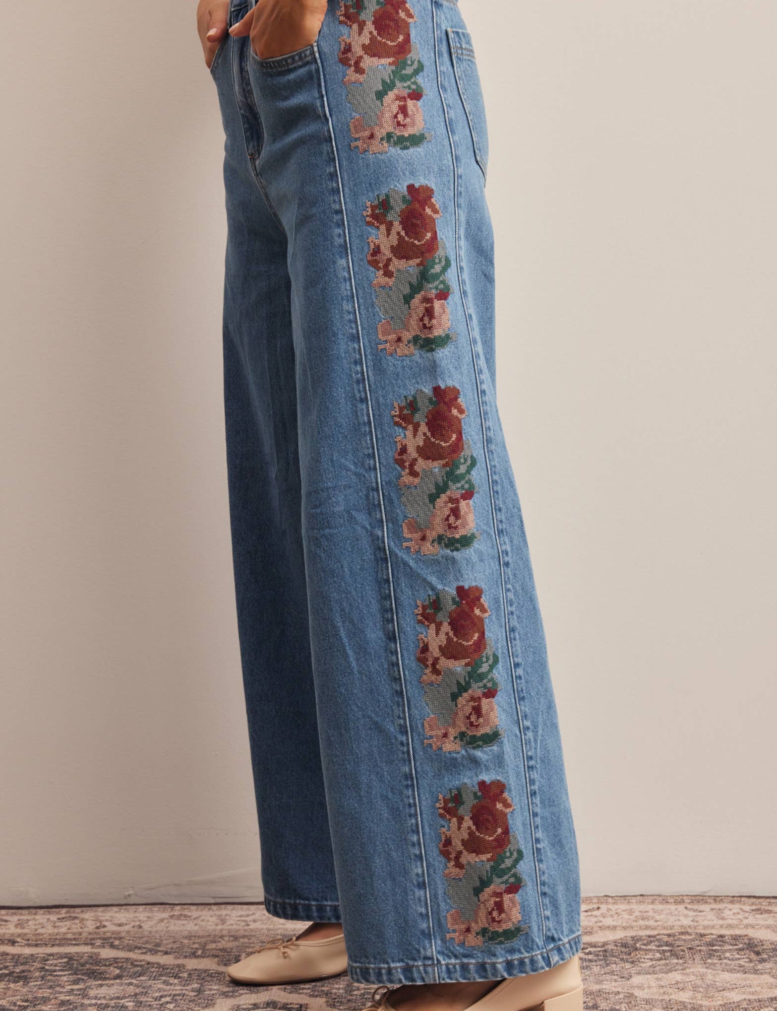 medium wash high rise wide leg jeans with rust and green floral embroidery along the side seams
