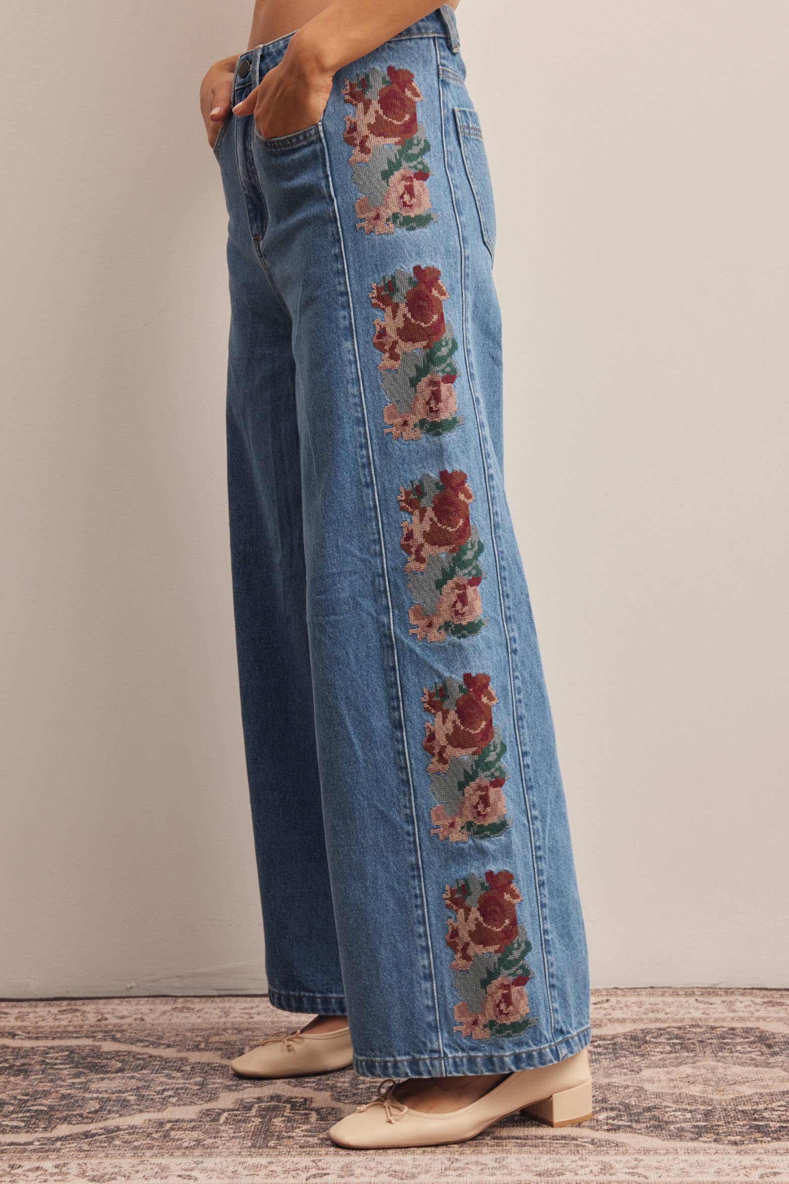 medium wash high rise wide leg jeans with rust and green floral embroidery along the side seams